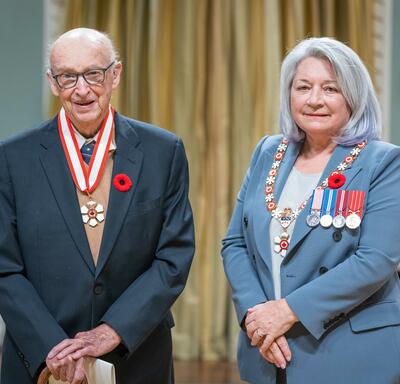 Peter Howard Russell is standing next to the Governor General.
