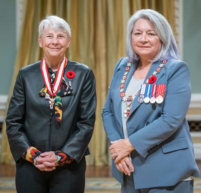 Sandra Louise Kirby is standing next to the Governor General.