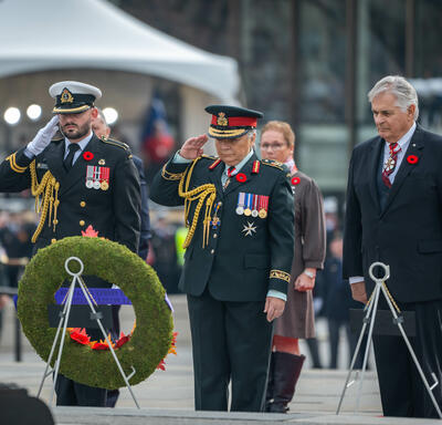Governor General Mary Simon is saluting after placing a wreath on a stand at the National War Memorial in Ottawa. Several people are standing behind her.