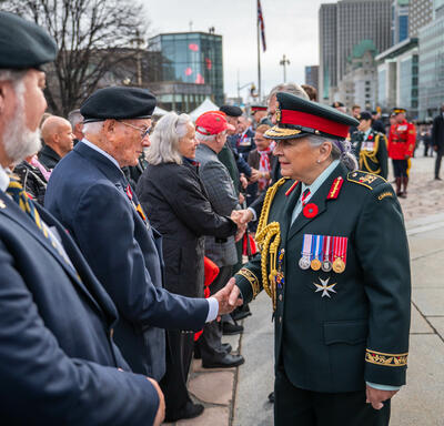 Governor General Mary Simon is shaking hands with a veteran. She is wearing the Canadian Army uniform. 