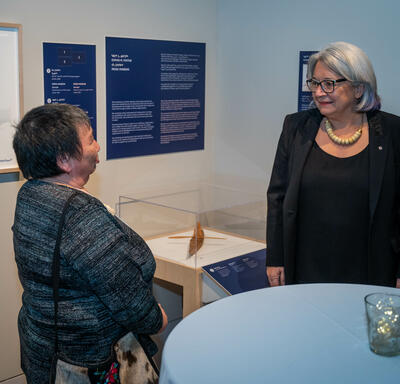 The Governor General is speaking with a woman at the Our Land, Our Art exhibition. 