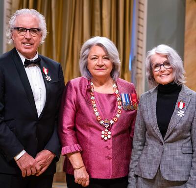 Governor General Simon is standing between a man and a woman who have medals pinned to their blazers.