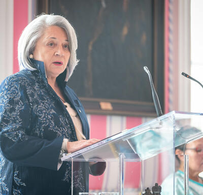 La gouverneure générale Mary Simon est debout à un pupitre et parle, dans la salle de la tente de Rideau Hall, lors d’un événement organisé à l’occasion de la Journée internationale des femmes.