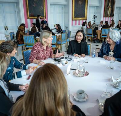 A group of women engage in conversation at a round table with Governor General Simon, in the Tent Room at Rideau Hall. 