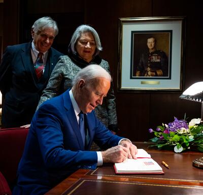 President Joe Biden signing a guest book. Governor General Simon and Mr. Whit Fraser are standing behind him.