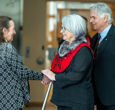 Governor General Mary Simon shaking the hand of a woman. Mr. White Fraser is standing behind the Governor General.