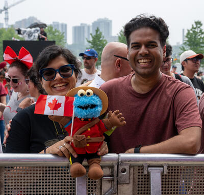 Les amateurs de la fête du Canada tenant une poupée Cookie Monster avec un drapeau canadien