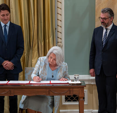 La gouverneure générale Marie Simon signe des documents officiels pendant que le premier ministre Justin Trudeau la regarde
