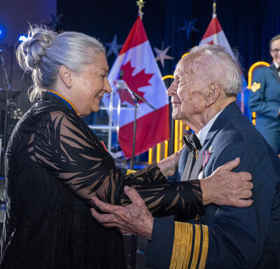 Governor General Mary Simon holds General Richard Rohmer while members of the Central Band of the Canadian Armed Forces watch in the background.