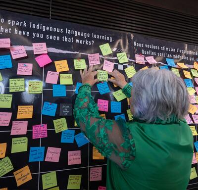 Governor General Mary Simon adding a post-it note to a wall filled with colourful messages.