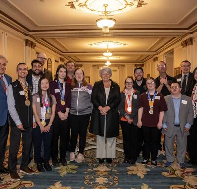 Governor General Mary Simon posing with a group of people involved in the Special Olympics. Several people are wearing medals.