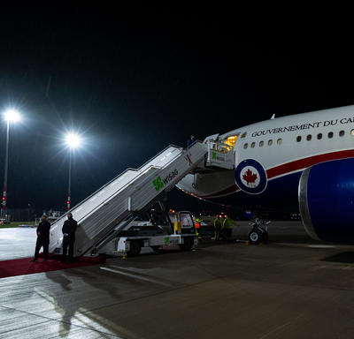 L'avion du gouvernement du Canada est sur le tarmac de l'aéroport. La porte de l'avion est ouverte et les escaliers sont ouverts en attendant que les passagers descendent. 