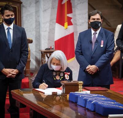 Governor General Mary Simon sitting at a table and signing a paper document.