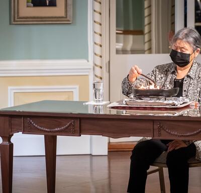 L’aînée Sally Webster est assise sur une chaise et allume le qulliq.