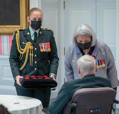 Governor General Mary Simon thanking a Canadian veteran for his service and presenting him with a poppy.