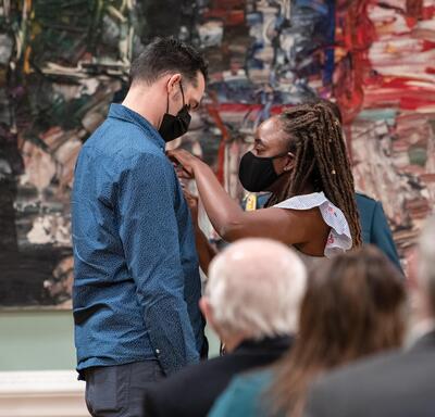 Une femme épingle une médaille sur la poitrine d’un homme.