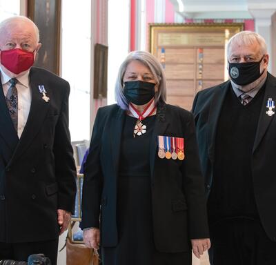 Governor General Mary Simon standing between two recipients.
