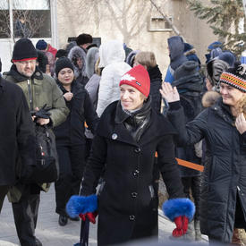 The Govenor General, Julie Payette, waves at a crowd. She is outdoors and walking next to Véronique Morin, spouse of astronaut David Saint-Jacques.