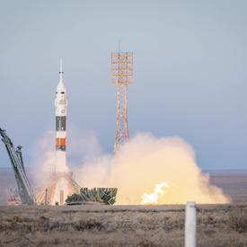 A rocket launches into space.  On the ground, we see fire and smoke.