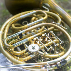 A photo of a French Horn laid down on the grass next to sheet music on the grounds of Rideau Hall