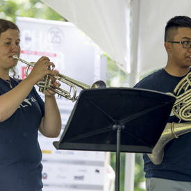 Deux musiciens de cuivres se produisent au Chamberfest 2018 sur le terrain de Rideau Hall, jouant respectivement de la trompette et du cor d’harmonie.