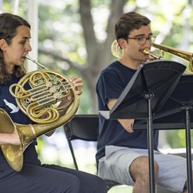 Two brass musicians perform at Chamberfest 2018 on the grounds of Rideau Hall, playing the French horn and trombone respectively.