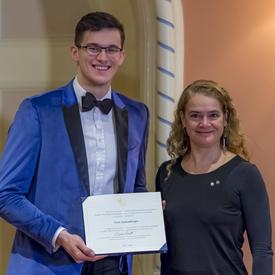 Sven Stammberger is holding her certificate and posing for a photo beside the Governor General. 