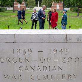 A photo of a stone marking the Bergen-op-Zoom Canadian War Cemetery, the Governor General in the background.