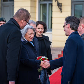 Governor General Simon shaking a man’s hand. Several other people are standing around them.