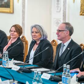 Governor General Simon sitting at a large table, with other people seated on either side of her. They each have a microphone in front of them.