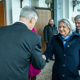 Governor General Simon shaking hands with Acting Chair of the City Council Harry Bogomoloff. Two people are standing behind them.