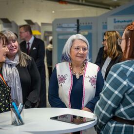 La gouverneure générale Mary Simon se tient debout avec plusieurs femmes. La femme à sa gauche lui parle.