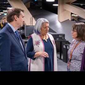 La gouverneure générale Mary Simon se tient entre un homme et une femme. La femme leur parle.