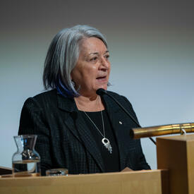 La gouverneure générale Mary Simon est debout sur un lutrin et s’adresse à une foule.