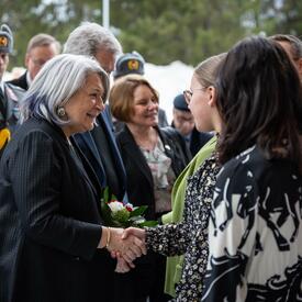 La gouverneure générale Mary Simon serre la main d’un étudiant. D’autres personnes les entourent.