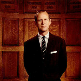 Portrait officiel du duc d’Édimbourg, en costume noir, chemise à rayures et cravate.