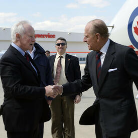 The Duke of Edinburgh shakes hands with Governor General David Johnston on the tarmac. 