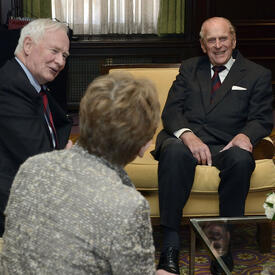 The Duke of Edinburgh is engaged in conversation with Governor General Johnston and Mrs. Sharon Johnston.
