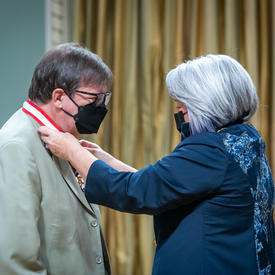 La gouverneure générale place une médaille autour du cou de Rémy Girard.