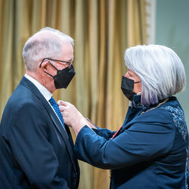 The Governor General is placing a pin on Thomas J. Foran’s suit jacket.