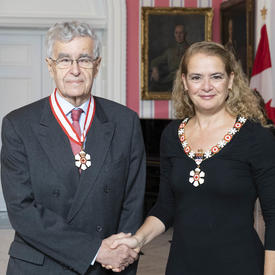 The Governor General, Julie Payette, stand next to Louis LeBel, retired justice of the Supreme Court of Canada. Both are wearing the Order of Canada isignias. 