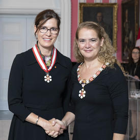 The Governor General, Julie Payette, stands next to Sophie D'Amours.  Both are wearing their Order of Canada insignias. 