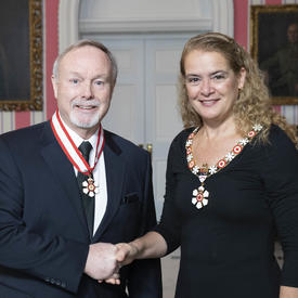 The Governor General, Julie Payette, stands next to Terence Matthews.  Both are wearing their Order of Canada insignias.