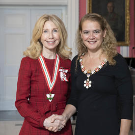 La gouverneure générale, Julie Payette, se tient debout aux côtés de Lynn Factor.  Tous deux portent l'insigne de l'Ordre du Canada.