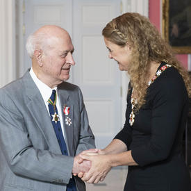 The Governor General, Julie Payette, shakes Kay Nasser's hand as they speak.  Both are wearing their Order of Canada insignias.