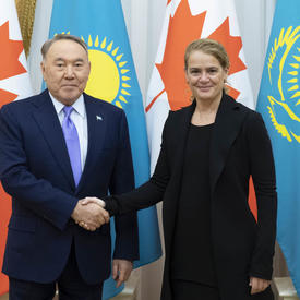 The Governor General shakes the hand of His Excellency Nursultan Nazarbayev, President of Kazakhstan.  They smile for the camera.  Behind them are Canadian and Kazakhstani flags.
