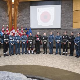 The Governor General, Mr. Thomas Irvine (President of the Legion) and a group of 15 Cadets and Junior Rangers stand in a semi-circle as an image of a digital Poppy is projected on the screen behind them.