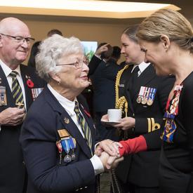 Governor General speaks and holds the hand of a veteran.
