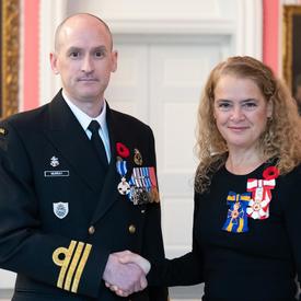 The Governor General stands next to recipient Commander Jeffrey Lawrence Murray who is wearing the Meritorious Service Medal (Military Division) he has just received on his naval uniform. 