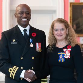 The Governor General stands next to recipient Lieutenant-Commander Paul Anthony Smith who is wearing the Meritorious Service Medal (Military Division) he has just received on his naval uniform. 